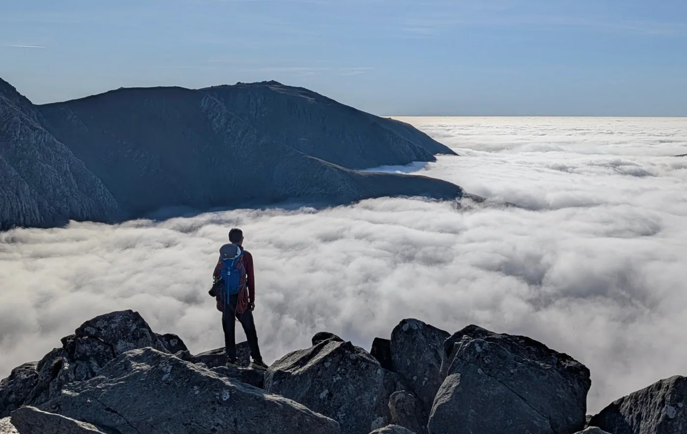 Simon Grogan looking across a cloud inversion from a rocky summit